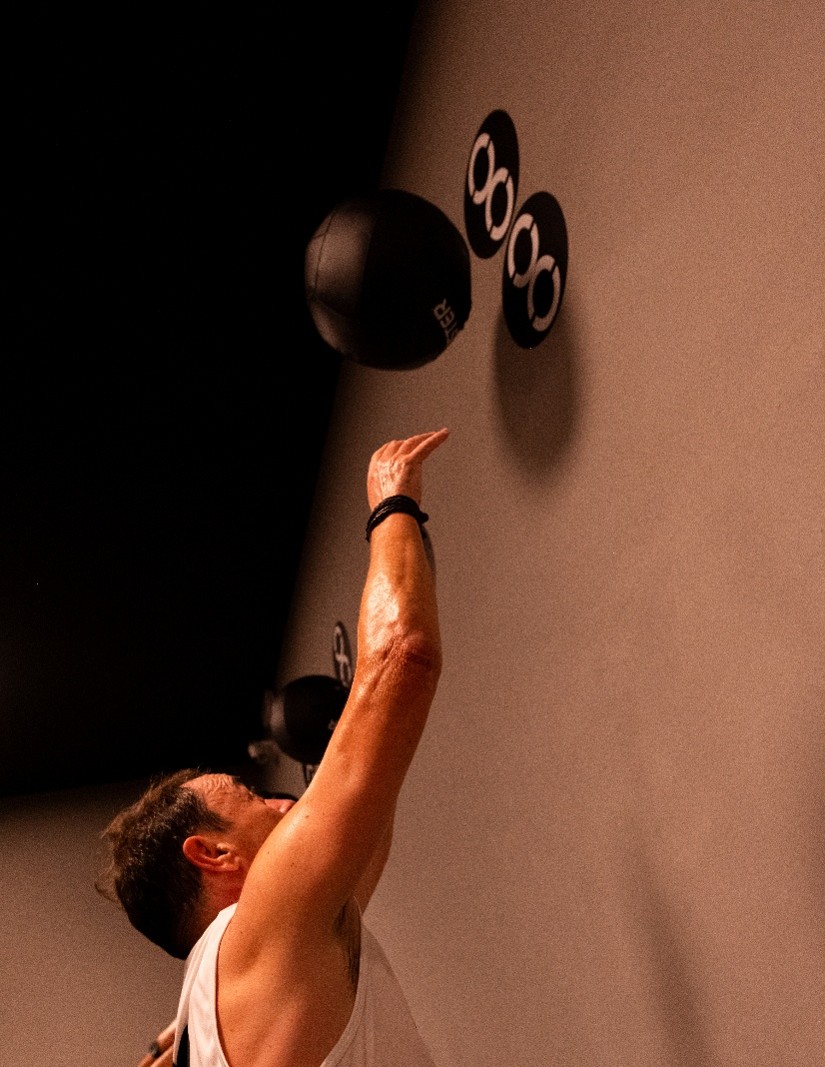 Deportista realizando un ejercicio de wall balls con balón medicinal durante un entrenamiento HYROX.
