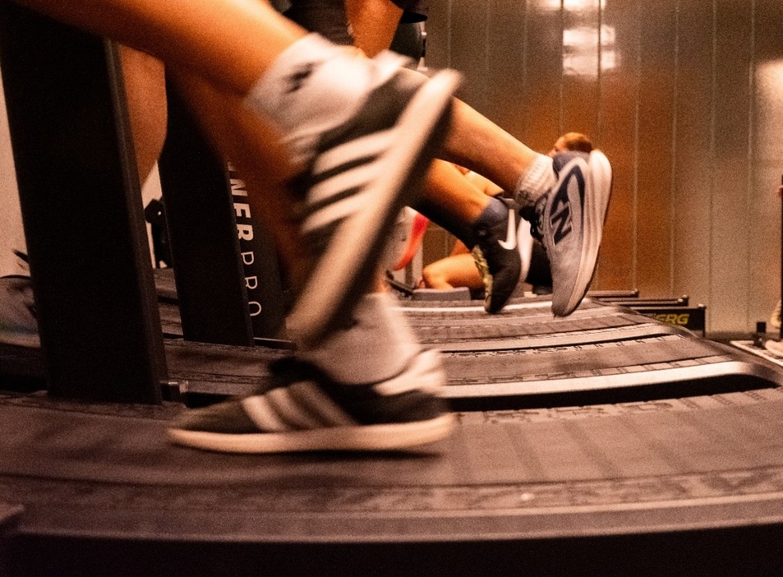 Personas corriendo en cintas durante una clase de HYROX.