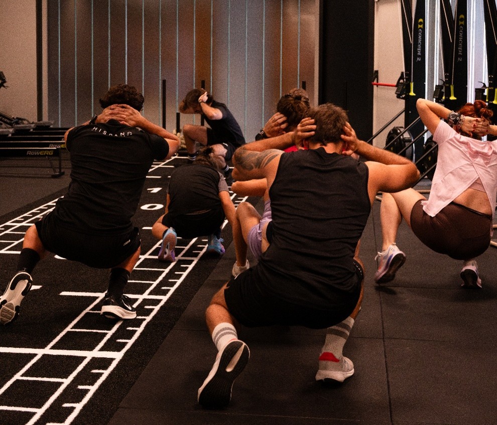 Grupo de deportistas realizando zancadas durante una clase de entrenamiento Hyrox.