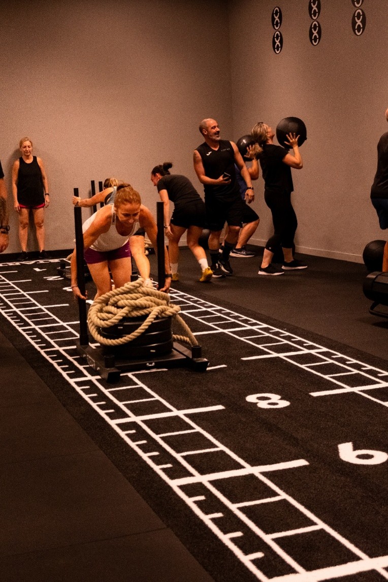 Participantes realizando ejercicios de fuerza con trineo durante un entrenamiento HYROX.