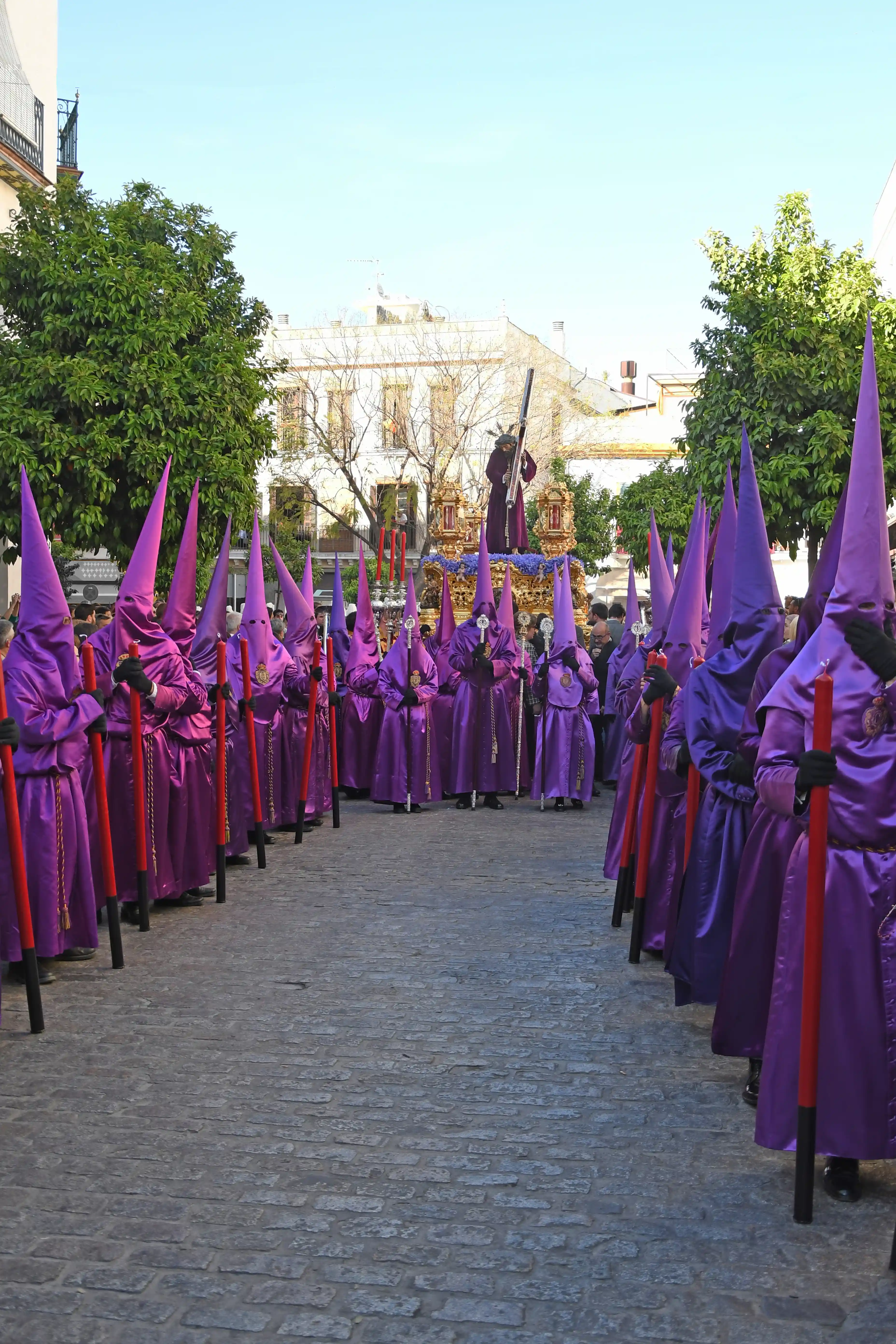 Cuarto premio 2023 concurso fotografía Semana Santa Hispano Happiness Club – nazarenos morados en procesión con paso al fondo.